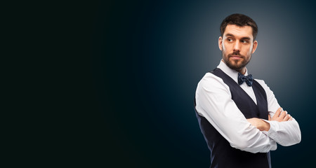 people concept - serious man in white shirt, waistcoat and bowtie over black background