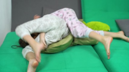 two kids fighting with pillows on sofa