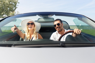 leisure, road trip, dating, couple and people concept - happy man and woman driving in cabriolet...
