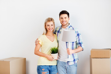 Fototapeta na wymiar home, people, repair and real estate concept - smiling couple with cardboard boxes, lamp and flower moving to new place