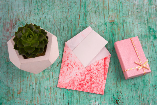 top view pink gift ,succulent potbox and envelope with white blank paper mock up shabby wooden background
