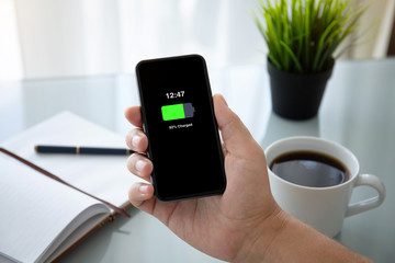 man hand holding phone with charged battery on the screen