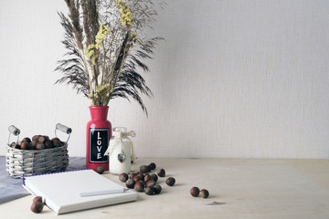 Still life on a wooden table. The concept of the notebook and attributes. The mood in the frame. Waiting for spring. Nuts and herbarium. Tinted photo