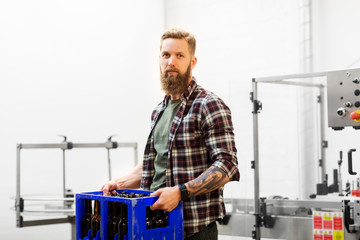 production, small business and people concept - man with bottles in box at craft brewery or beer plant