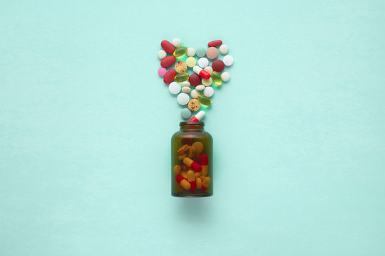 Little glass bottle with pills spilled over a table