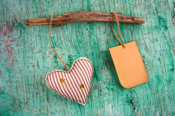 cute stripped soft toy heart and old paper label with place for text  on a vintage wall