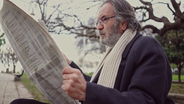Old man reading newspaper in the park