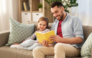 family, leisure and people concept - happy father and daughter reading book at home