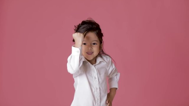cute little child girl in white shirt shows different emotions on pink background.