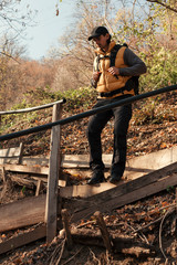 Man hiking in nature and walking on wooden stairs trough forest.