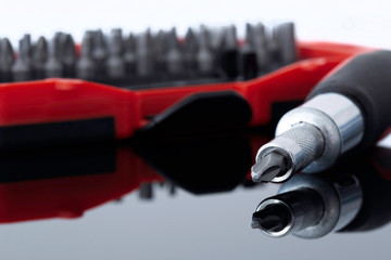 Fototapeta premium Screwdriver with phillips head with various bits in a case in the background reflected on a glass surface
