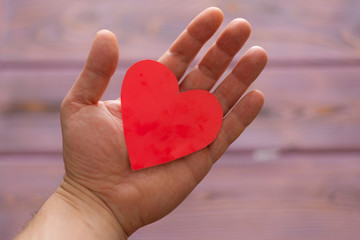 Obraz premium Love heart in male hand. The concept of love, the proposal of the heart, sympathy, Valentine's Day.