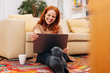 Woman sitting on floor with tablet and smiling
