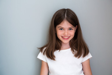 Portrait of a beautiful young girl in a white T-shirt on a gray background, concept advertising