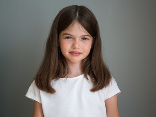 Portrait of a beautiful young girl in a white T-shirt on a gray background, concept advertising