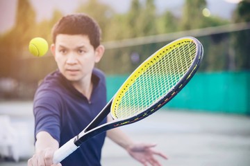 Man holding racket about to hit a ball in tennis court - people in tennis game match concept