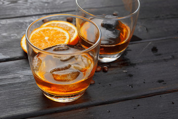 Whiskey or liqueur, coffee beans and orange cut on wooden background. Seasonal holidays concept.