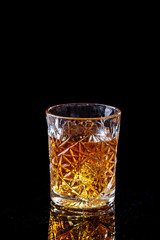 concept of alcoholism, loneliness, dependence. A bottle of whiskey, a glass of whiskey and with ice, a cigar with smoke on a black table, on a black background. Elite drink for masculine relaxation