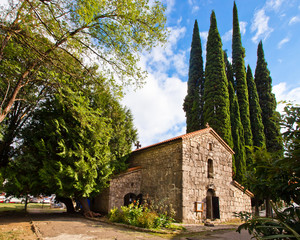 Fototapeta na wymiar church against the backdrop of greenery and high cypress trees on the Black Sea coast of the Caucasus