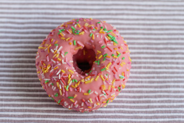 Donut with colorful sprinkles on table  background.