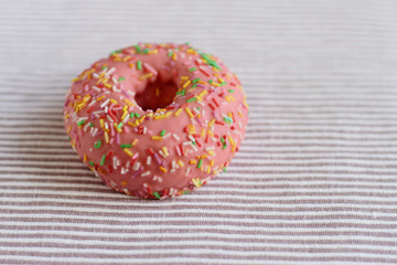 Donut with colorful sprinkles on table  background.