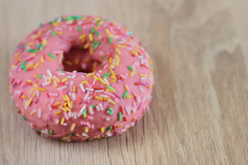 Donut with colorful sprinkles on table  background.