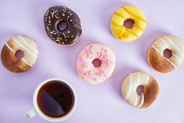 Flat lay top view colorful donuts on bright purple paper. Creative food decor background. Junk food concept