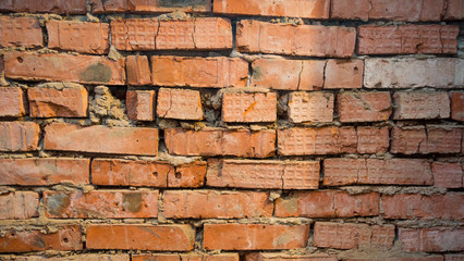 A wall of red brick, laid sloppy on gray cement.