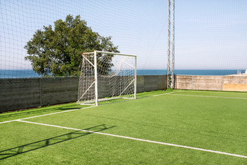 Soccer goal door with white net. Football goal at soccer field with green grass and sport stadium on campus, bleachers, white line and soccer field corner. Sports elements, equipment and environment.