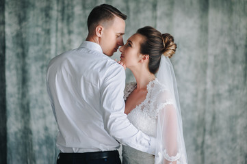 Beautiful newlyweds sitting in studio on sofa and hugging. The bride and groom on a blue sofa.