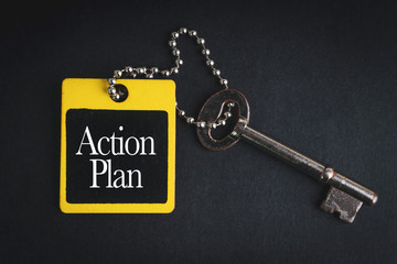 ACTION PLAN inscription written on wooden tag and key on black background with selective focus and crop fragment. Business and education concept
