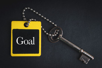 GOAL inscription written on wooden tag and key on black background with selective focus and crop fragment. Business and education concept