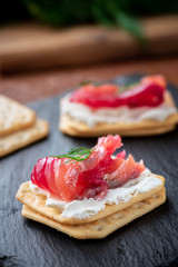 Appetizer cracker with salmon on a black board. Gravlax