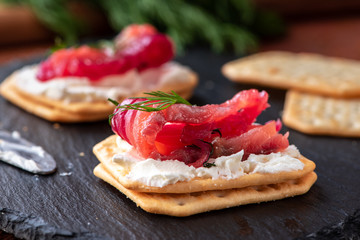 Appetizer cracker with salmon on a black board. Gravlax