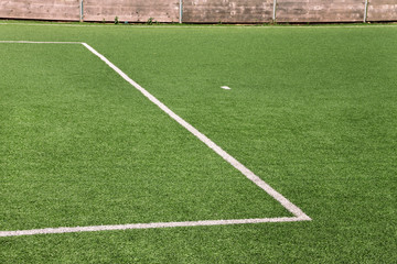 Part of sport soccer stadium and artificial turf football field. Detail, close up of green grass with white lines, goal line, corner line. Focus football field selected background, texture, wallpaper.