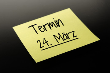 Termin 24. März - gelber Notizzettel dunkler Hintergrund