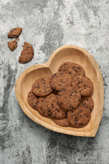 Chocolate chip cookies on heart-shape plate on grey stone background