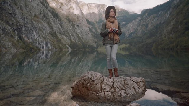 Attractive photographer with a retro camera by the lake