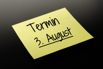 Termin 3. August - gelber Notizzettel dunkler Hintergrund