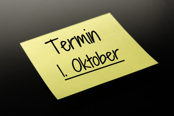 Termin 1. Oktober - gelber Notizzettel dunkler Hintergrund