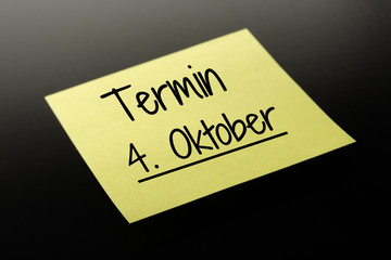 Termin 4. Oktober - gelber Notizzettel dunkler Hintergrund