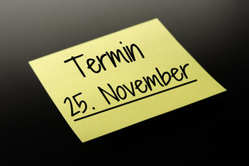 Termin 25. November - gelber Notizzettel dunkler Hintergrund