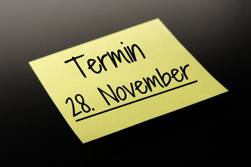 Termin 28. November - gelber Notizzettel dunkler Hintergrund