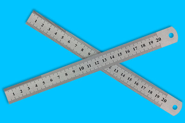 Pair of metal straightedges with digits and scale on blue background