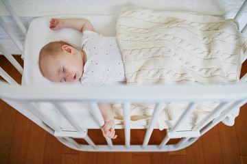 Fototapeta na wymiar Baby sleeping in co-sleeper crib attached to parents' bed