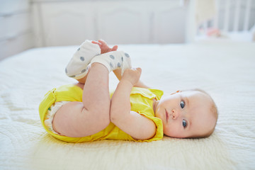Adorable baby girl removing sock from her foot