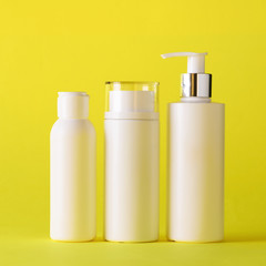 White cosmetic tubes on yellow background with copy space. Skin care, body treatment, beauty concept. Square crop