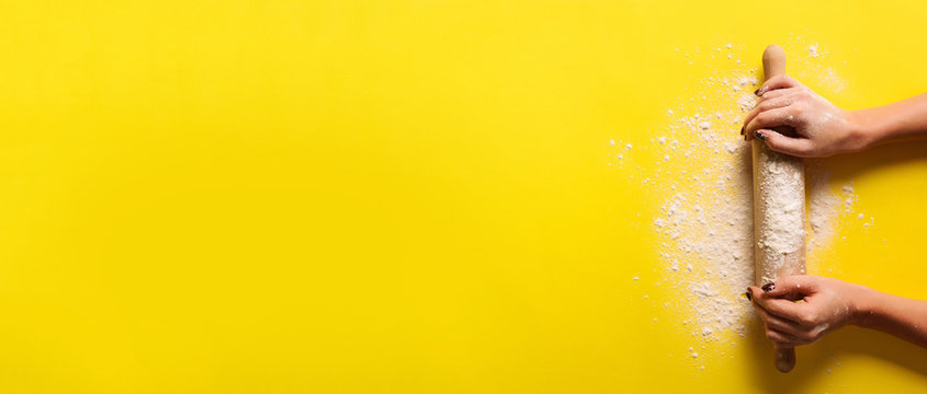 Baking flat lay with rolling pin, flour on yellow paper background. Bake menu, recipe, homemade pastry concept. Top view. Banner with copy space for your text