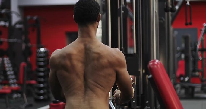 Naked black man exercising in the gym.