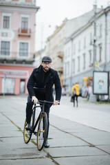 Bearded young businessman riding bicycle to work on urban street